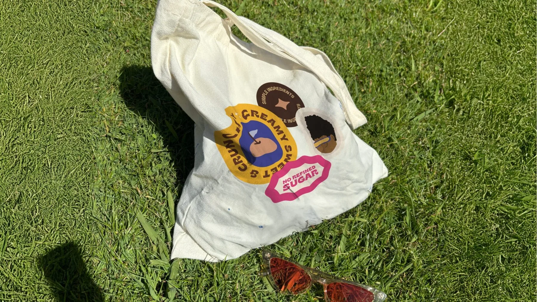 CocoFro tote bag with flavour badges photographed on grass